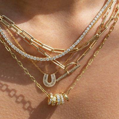 a stack of multiple yellow gold necklaces layered on one another