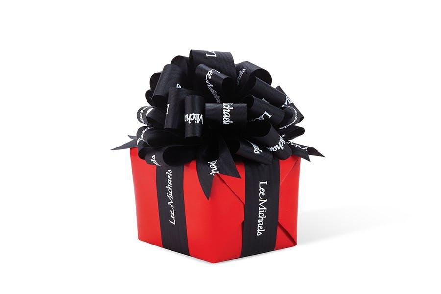 A red gift box with black ribbon branded with the Lee Michaels Logo